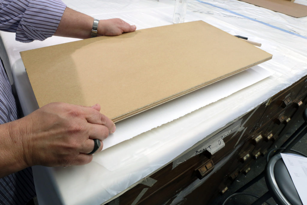 Position the second board on top of the second blotting paper sheet, and place weights on top of the board.